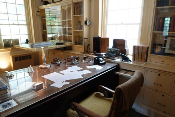 a wooden desk and chair with papers on top