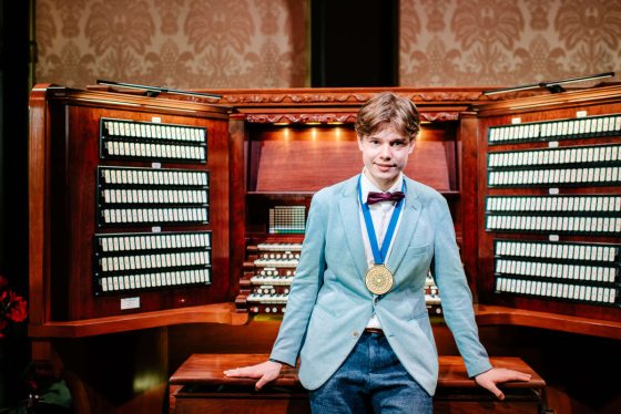 person sitting on the bench in front of the organ