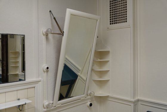 A mirror on a wall of a white dressing room