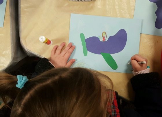a child drawing an illustration on a piece of paper 